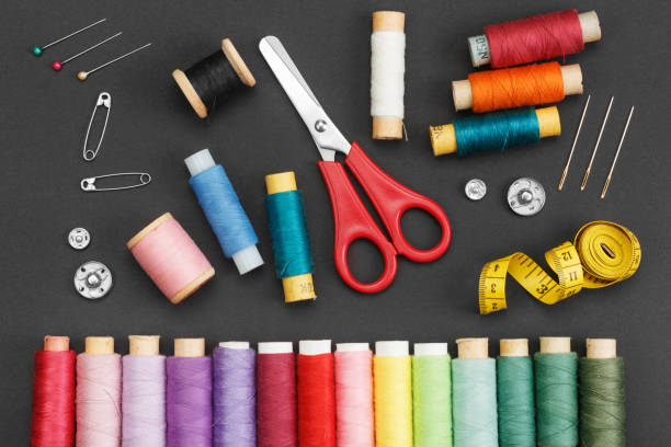 istock Colored thread coils, scissors, buttons, needles, pin and a tailor meter on a black background. 1204406998