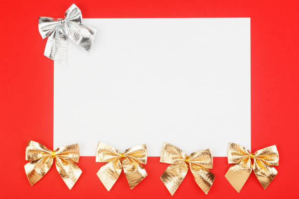 istock Blank white paper with golden and silver holidays bows on red background. 1204407672