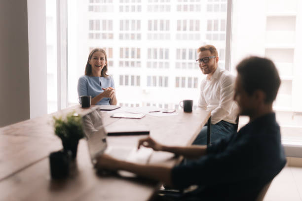 istock Three young businesspeople laughing in modern office room. 1204407980