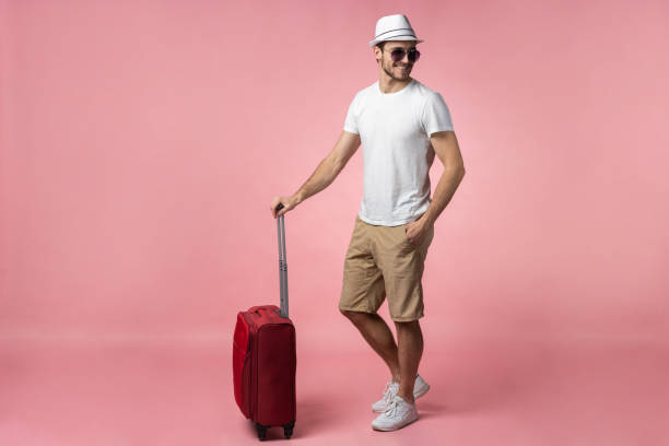 istock Man traveler with suitcase, passport and ticket on color background. 1204409507