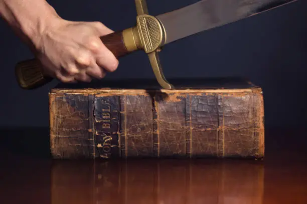 Strong male hand with sword and Bible