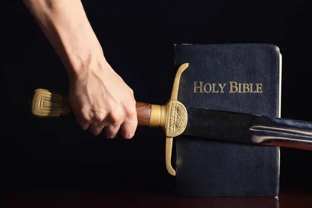 Strong male hand with sword and Bible