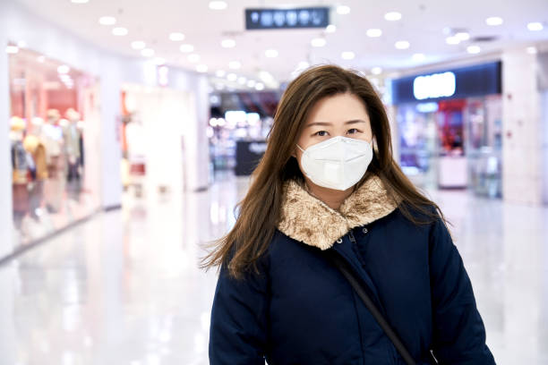 istock Person wearing protective mask against transmissible infectious diseases and as protection against pollution and the flu. East Asia woman commuter in the mall 1204411232
