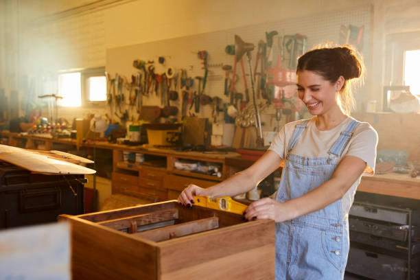 istock Smiling young woman using a level in her woodworking shop 1204416188