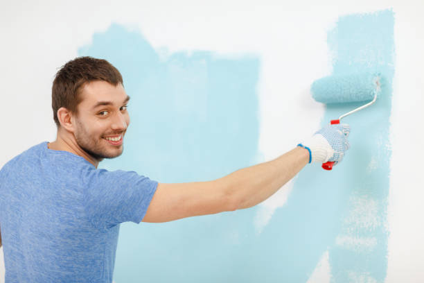 istock smiling man painting wall at home 1204416799