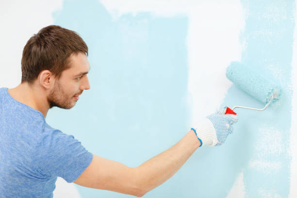 istock smiling man painting wall at home 1204416807