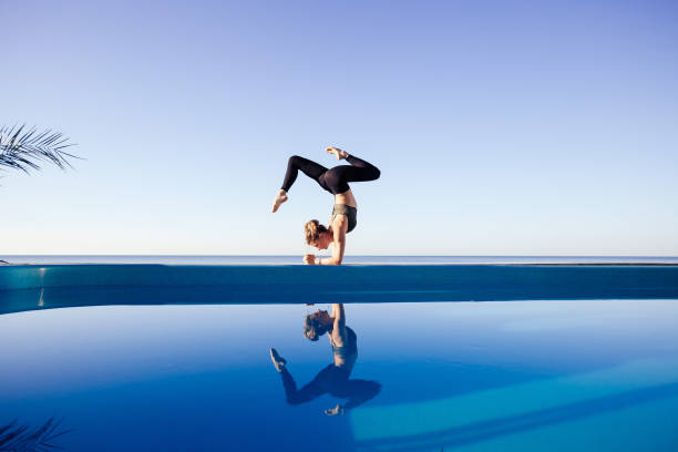 młoda atrakcyjna kobieta praktykująca jogę - blue water swimming pool sports and fitness zdjęcia i obrazy z banku zdjęć