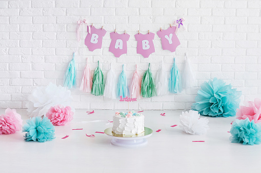 Decorated area for first baby birthday with a white brick wall on background. For smash cake photosession.