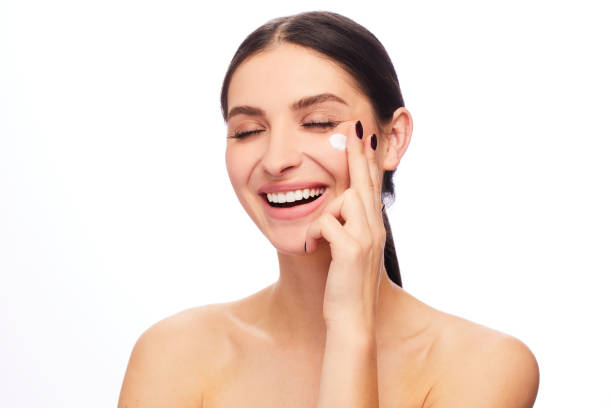 istock Laughing young woman applying cream to her cheek 1204426111