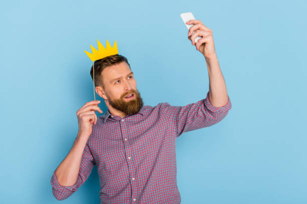 istock man holding paper crown and taking selfie on blue background 1204426822