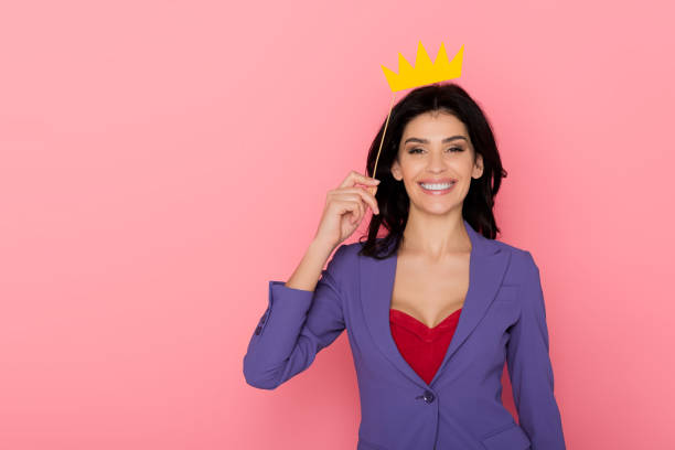 istock smiling woman holding paper crown on pink background 1204426962