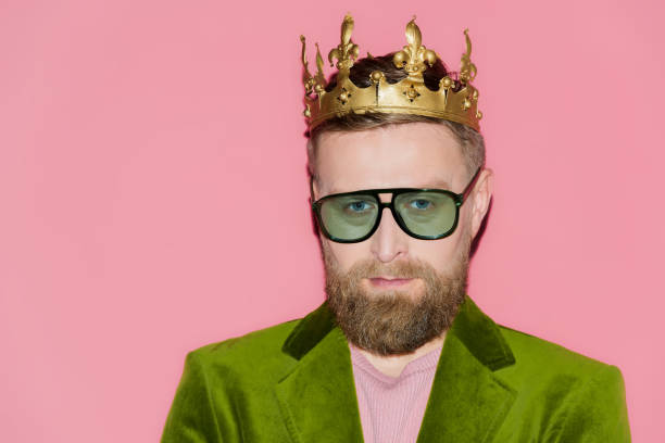 istock handsome man in velour jacket and crown looking at camera isolated on pink 1204426965