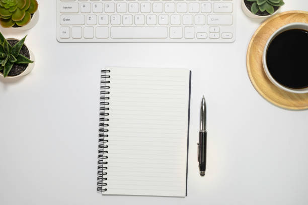 istock Flat lay, White office desk table. View from above with keyboard, pen, notebooks and cup of black coffee on wooden plate. Top view with copy space. Business concept. 1204427023