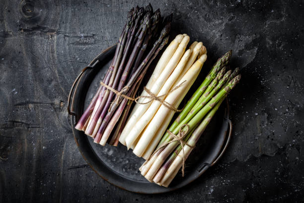 bunches of fresh green, purple, white asparagus on vintage metal tray over dark grey rustic background. top view, copy space - green asparagus imagens e fotografias de stock