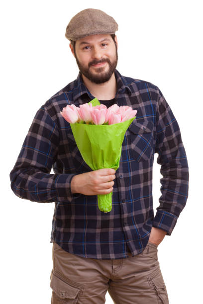 白い背景に孤立したピンクのチューリップの花束を持つひげを生やした若いハンサムな男。母の日、バレンタインデー、イースターと驚きのコンセプト。 - single flower flower mothers day easter ストックフォトと画像