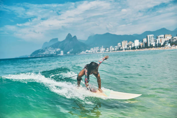 Beautiful little surfer rides on surfboard stock photo