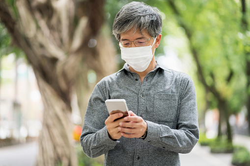 Worried senior Asian man wearing a protective mask in the city streets because of pollution