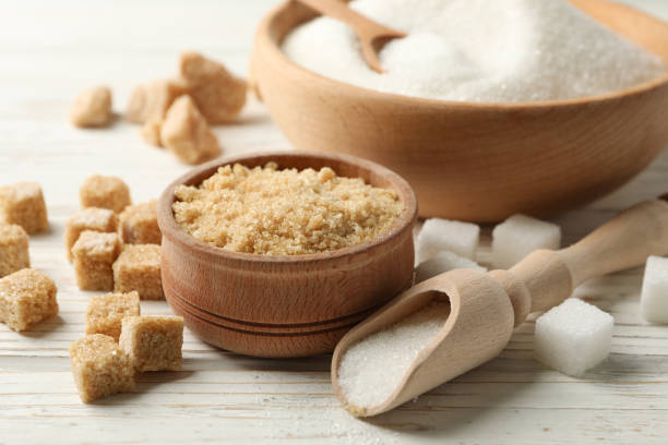 istock Bowls with sugar on white wooden background, close up 1204433671
