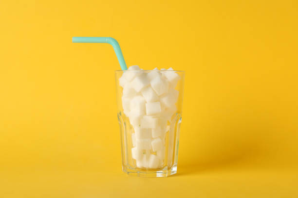istock Glass with sugar cubes and straw on yellow background, space for text 1204434995