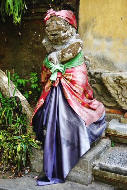 istock Ancient carved stone statue with eroded details draped in colorful fabric outside an ancient temple in Bali Indonesia 1204435080