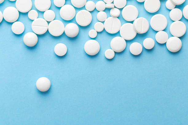 istock scattered white pills on a blue table. Layout for special offers such as advertising or other ideas. The concept of medicine, pharmacy and healthcare. Space for copy. 1204435252