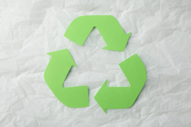 istock Recycling sign on white crumpled paper background, top view 1204435270