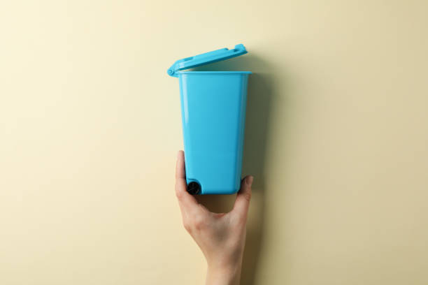 istock Female hand holding recycle bin on beige background, top view 1204435312