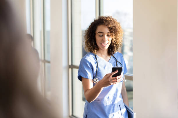 istock Female doctor text messages as she walks down corridor 1204436283
