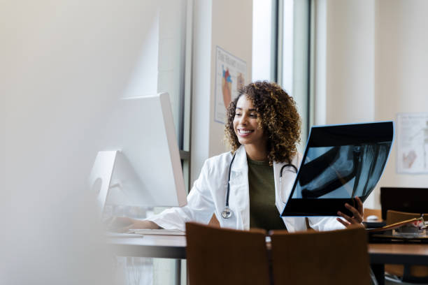 istock Confident doctor smiles while comparing x-ray with results on desktop 1204436290