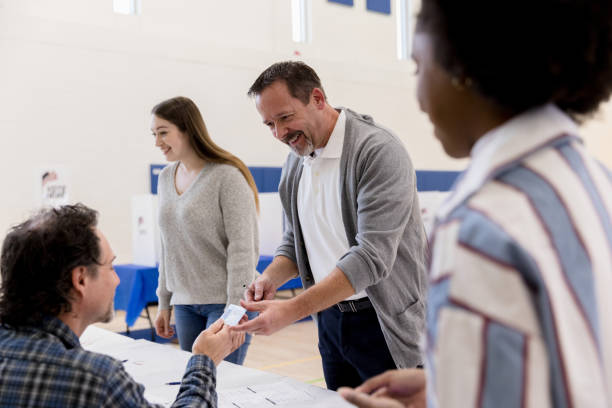istock Mature man hands ID to polling place volunteer 1204436307