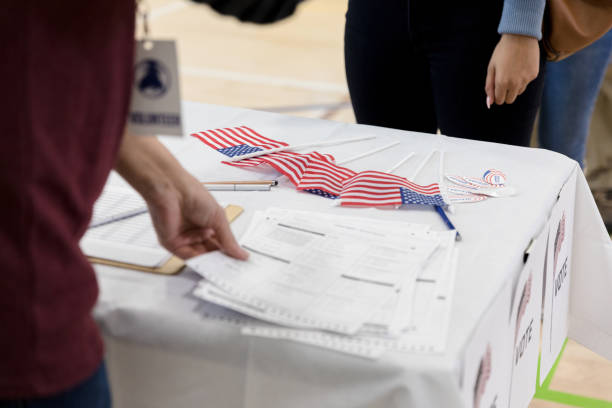 istock Volunteer works at table with documents, flags and stickers 1204436349