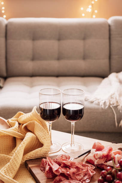 Red wine and cold cutes meat indoors on tableCozy home interior setting paleo food, ham, salami, grapes and red wine