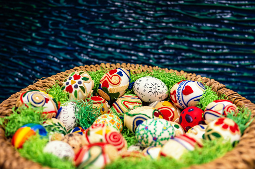 Homemade handmade painted Easter eggs on striped tablecloth decorated with prunus spinosa blackthorn sloe white flowering branch, green leaves