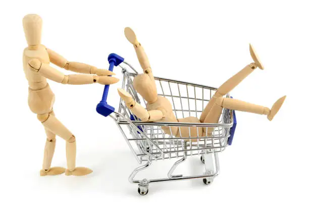 two wooden mannequines shopping with shopping cart.