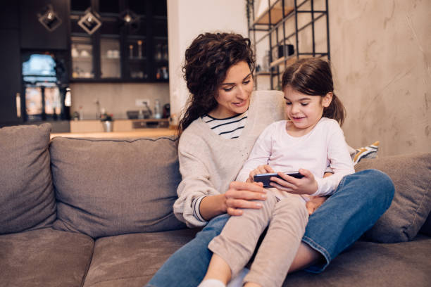 istock Girl sitting on her mother's lap and using smartphone 1204439567
