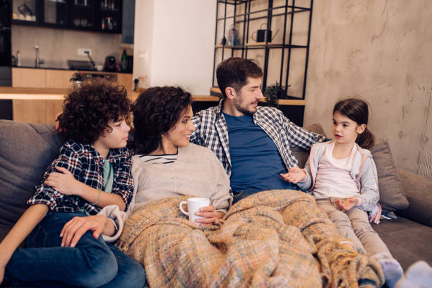 istock Young couple and their two kids relaxing on the sofa 1204439568