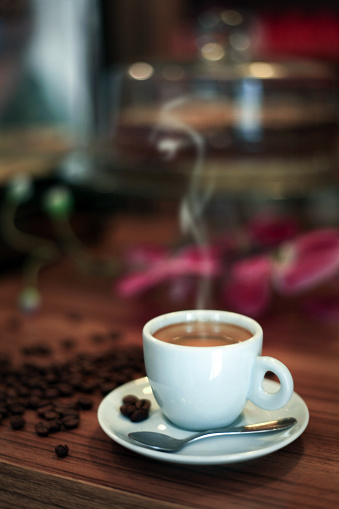 istock A white cup of hot coffee on a table. Coffee beans scattered near the cup 1204440573