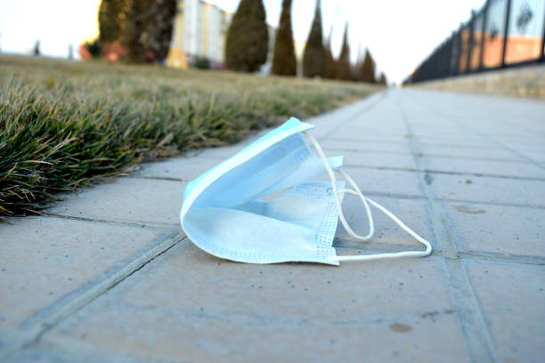 abandoned used medical mask on the sidewalk empty street