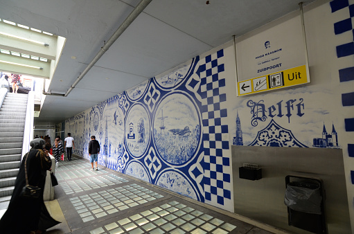 Delft, the netherlands, august 2019. The famous blue and white ceramics: here a mural takes up this symbolic theme of the city. People walk along the wall