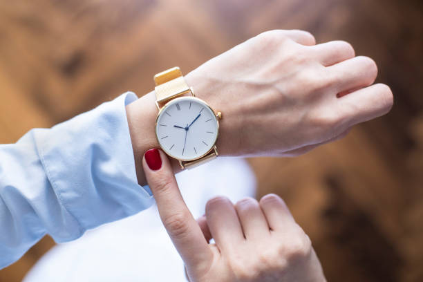 junge frau überprüft die zeit auf der uhr - handgelenk stock-fotos und bilder