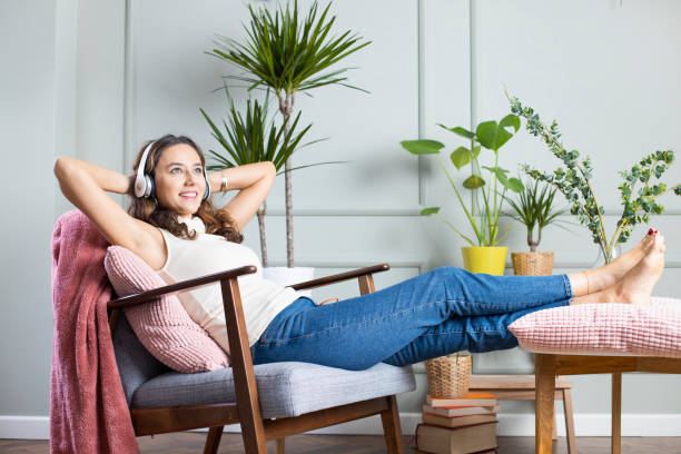 自宅で音楽を聴く若い女性 - armchair comfortable relaxation headphones ストックフォトと画像