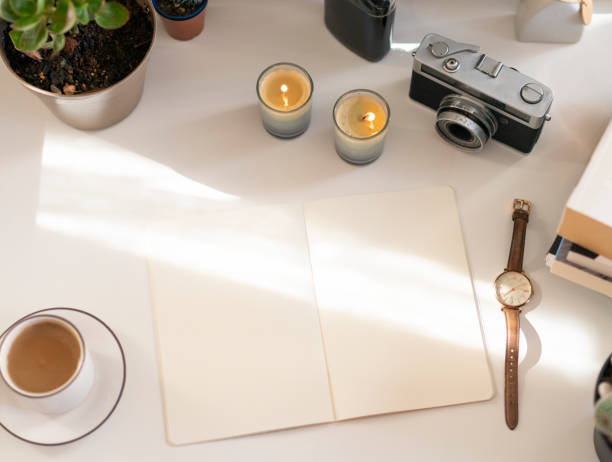 Blank open vintage notebook on table with books, candles camera and coffee