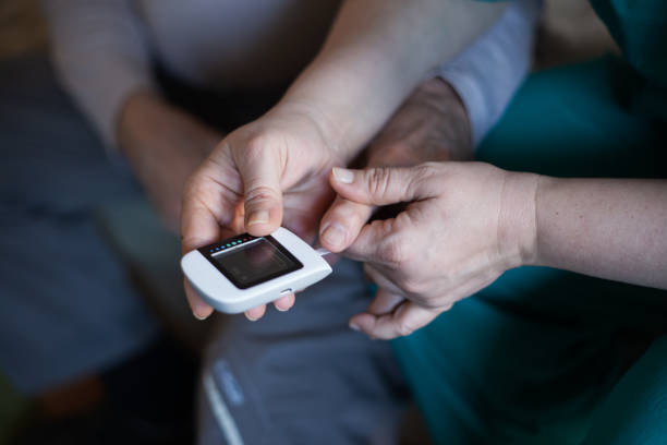 istock Nurse helping an elderly man to check blood sugar. 1204447051