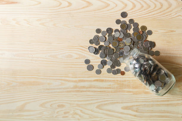 Collected coins inside a clear glass jar representing savings and financial growth