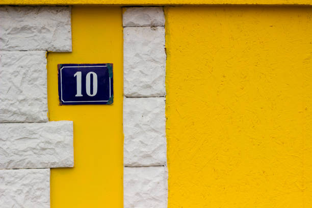żółta ściana z tablicą rejestracyjną domu 10 - plastering station zdjęcia i obrazy z banku zdjęć