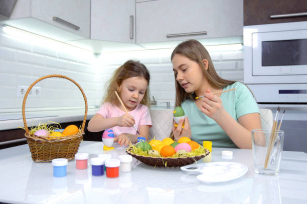 istock Happy easter. Two sisters painting Easter eggs. Happy family children preparing for Easter. Cute little child girl wearing bunny ears on Easter day 1204451820