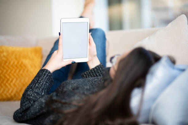 istock Woman with digital tablet in her hand relaxing on sofa at home 1204453656