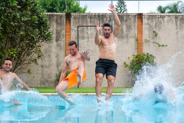 istock Four friends jumping into swimming pool 1204458483