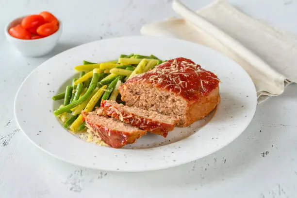 Meatloaf topped with tomato sauce with green beans