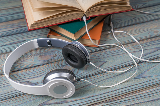 Books with headphones on a wooden table. Concept audiobook, technology, education, listen to book
